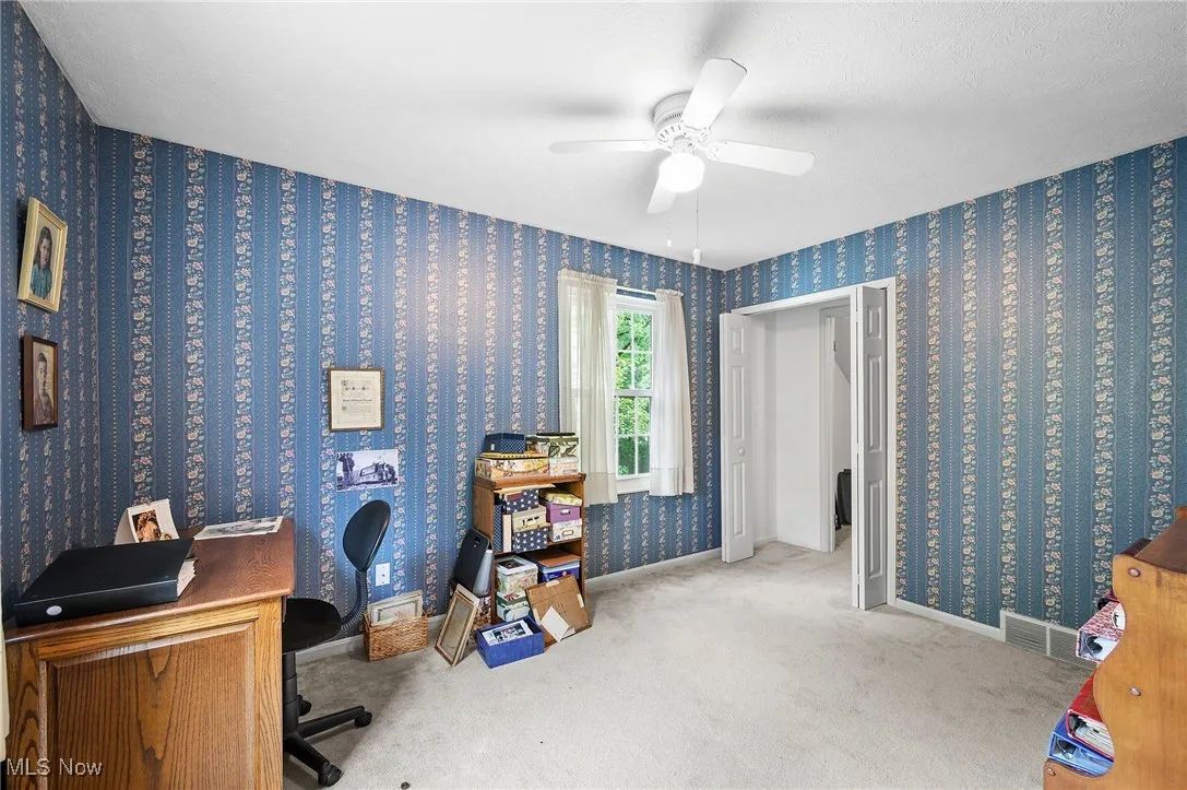 Carpeted home office featuring baseboards and a ceiling fan