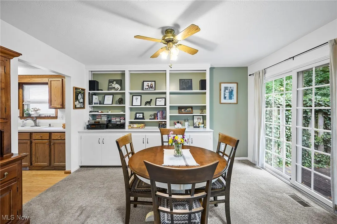 Dining area with light carpet and a ceiling fan