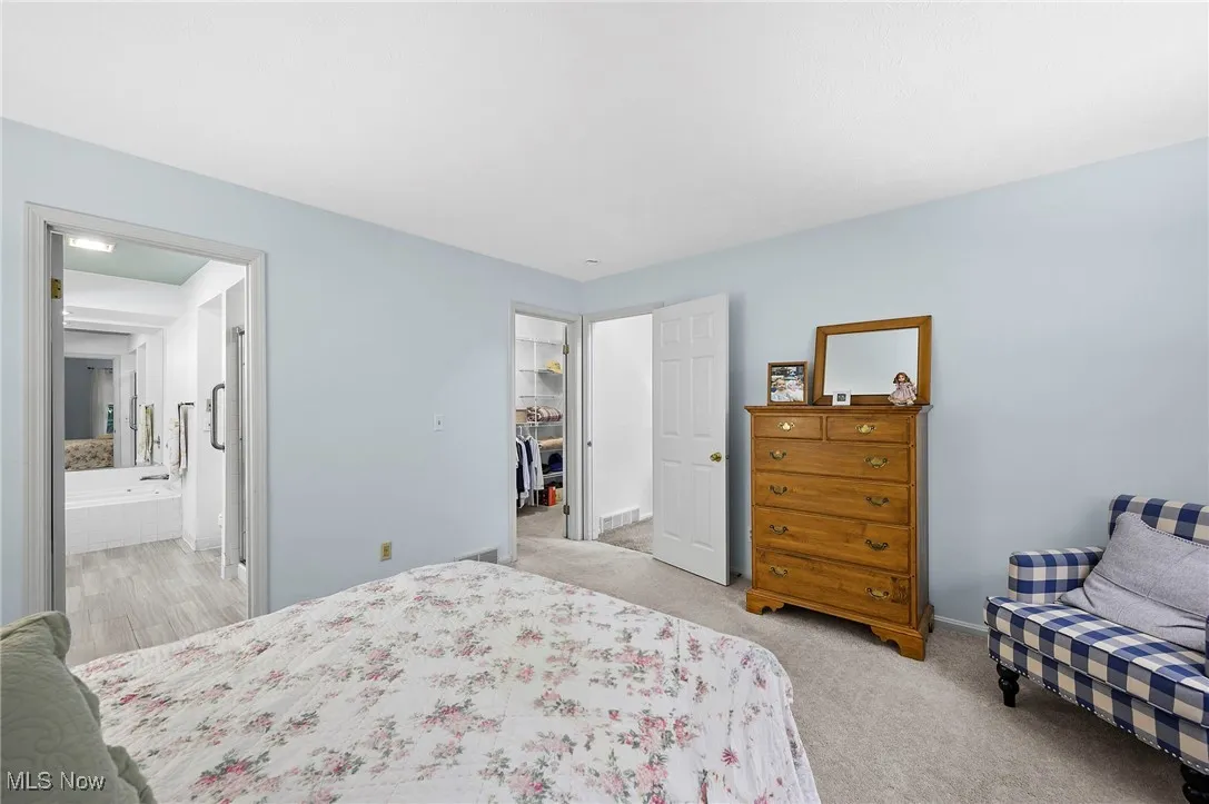 Bedroom featuring light colored carpet and ensuite bathroom