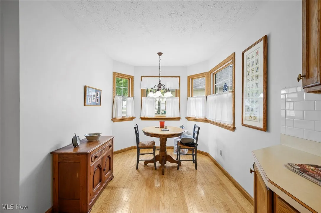 Dining area featuring a textured ceiling, light wood-style flooring, and a chandelier