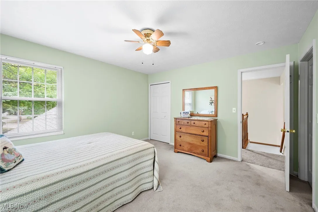 Bedroom featuring light colored carpet, ceiling fan, and a closet