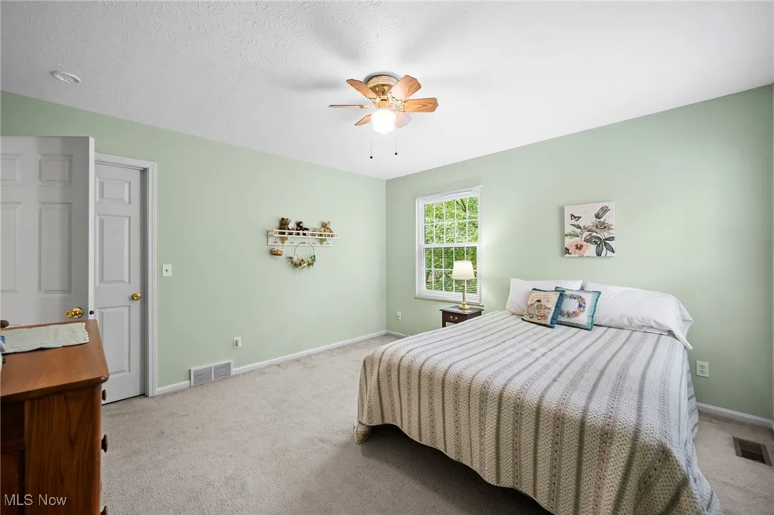 Carpeted bedroom featuring a ceiling fan and a textured ceiling