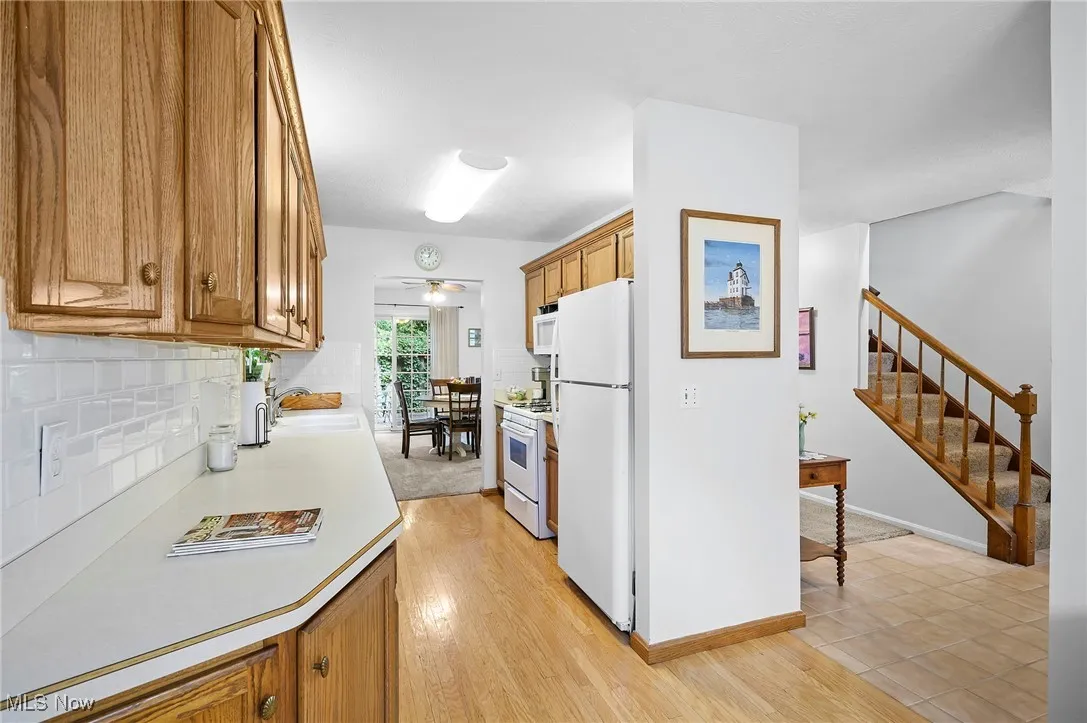 Kitchen with brown cabinets, light countertops, backsplash, and ceiling fan