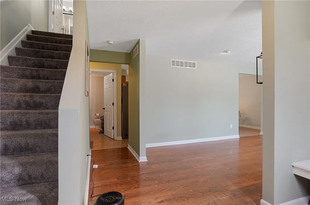 Staircase with wood finished floors and a textured ceiling