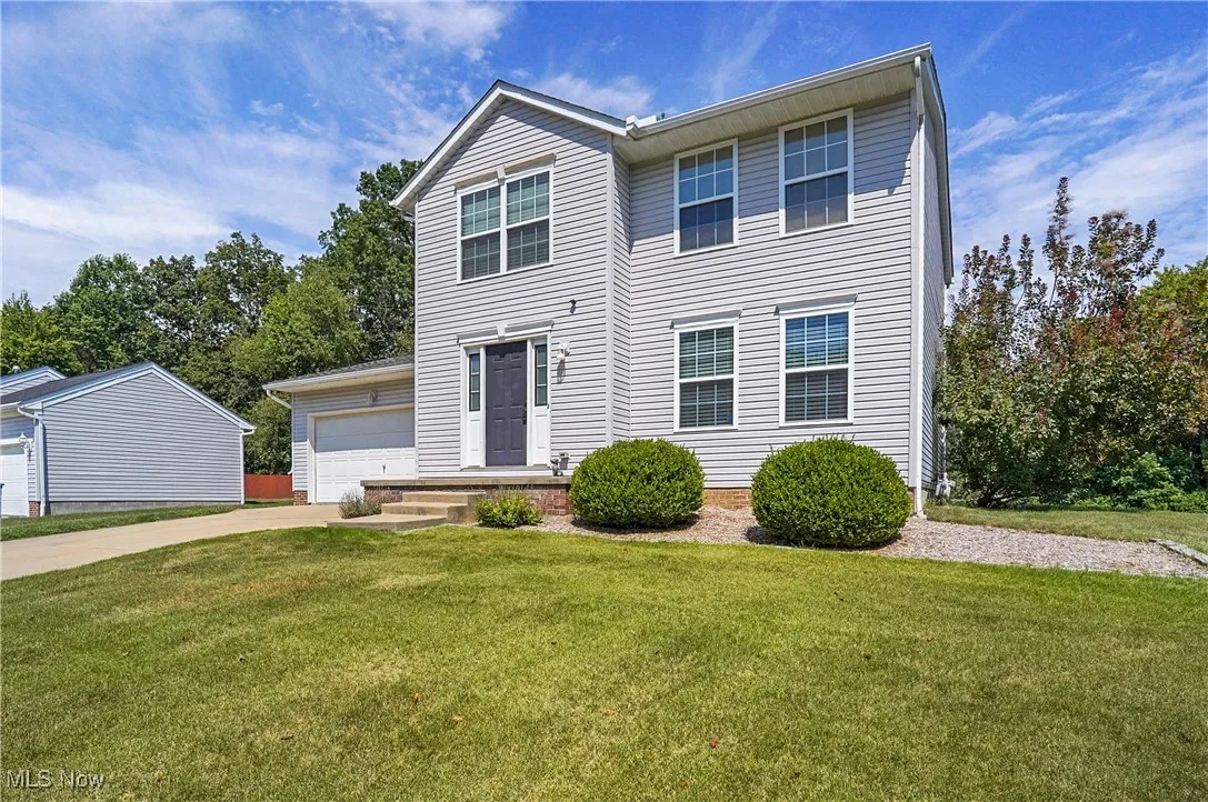 View of front facade with a front yard, concrete driveway, and an attached garage