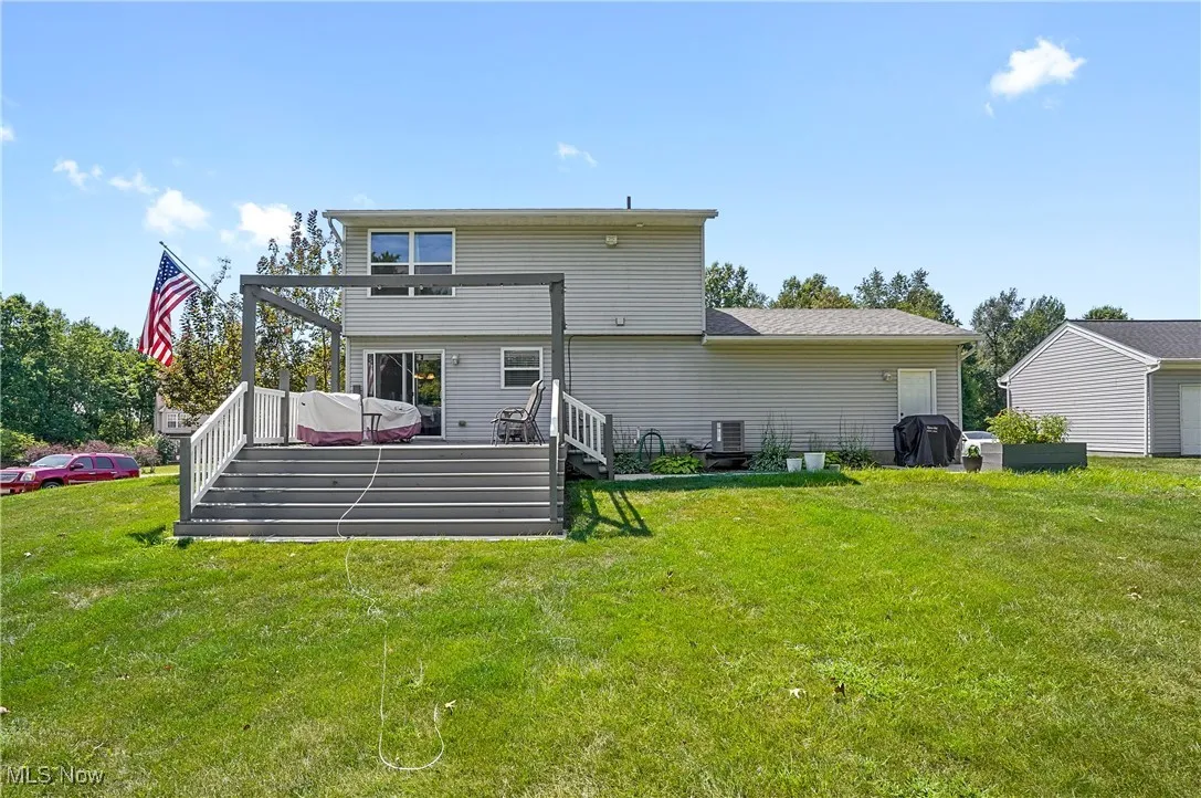 Back of property with a deck, a yard, and stairway