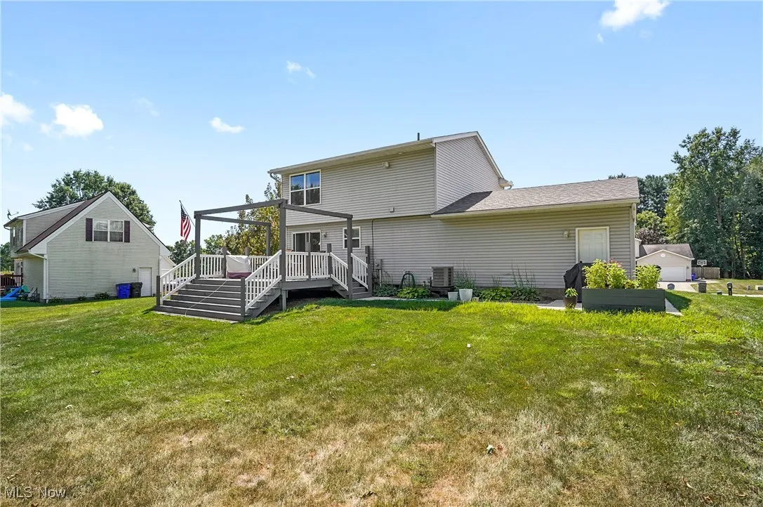 Back of house with a yard, a deck, and stairs
