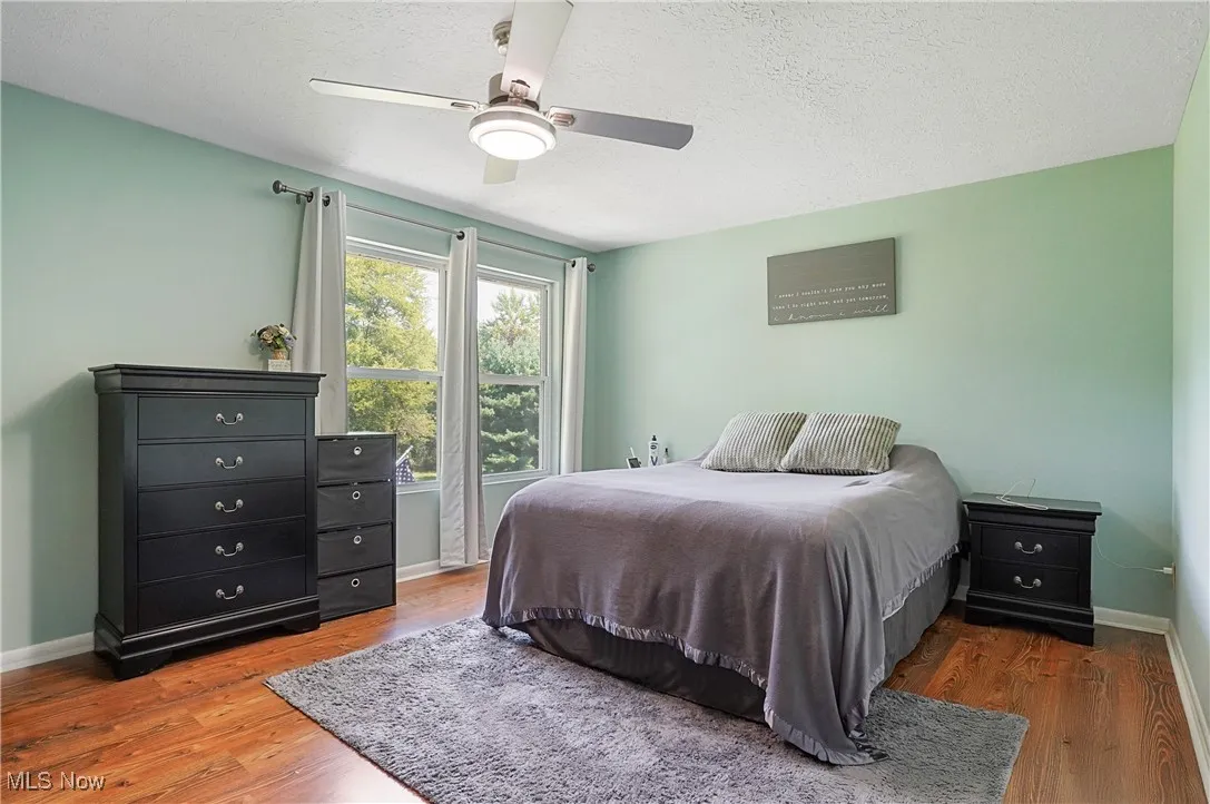 Bedroom featuring a textured ceiling, wood finished floors, and a ceiling fan