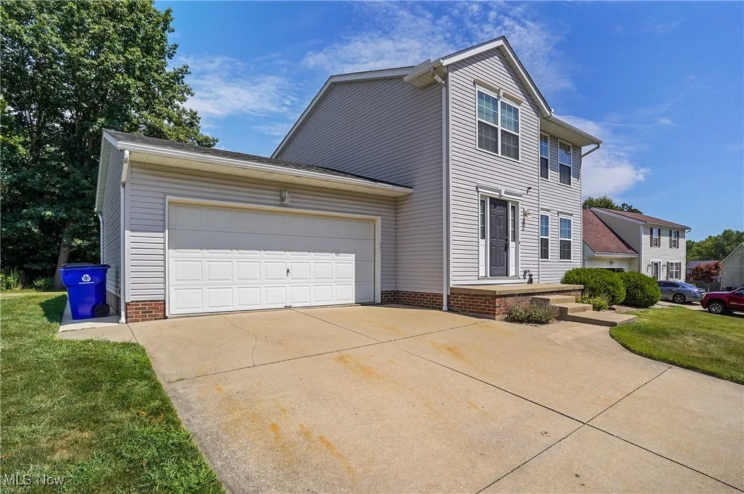 View of front of home with an attached garage, concrete driveway, and a front lawn