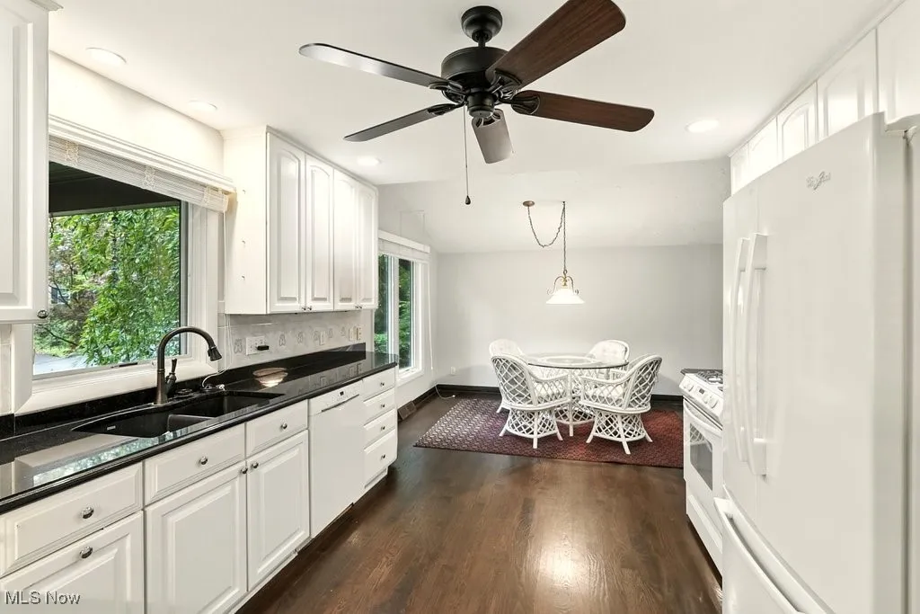 Kitchen featuring white appliances, white cabinetry, dark wood-type flooring, hanging light fixtures, and recessed lighting