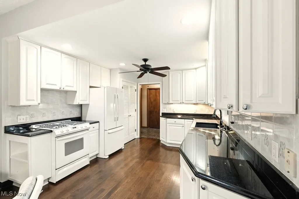 Kitchen featuring tasteful backsplash, white cabinets, white appliances, dark wood-type flooring, and recessed lighting