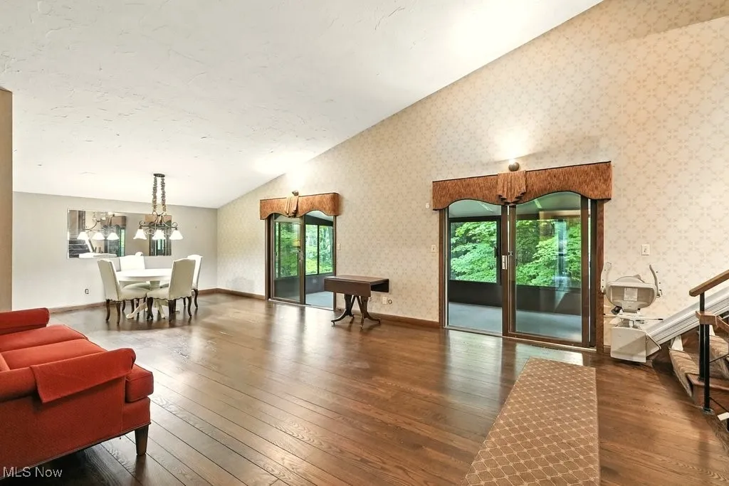 Living room with hardwood / wood-style flooring, plenty of natural light, vaulted ceiling, and wallpapered walls