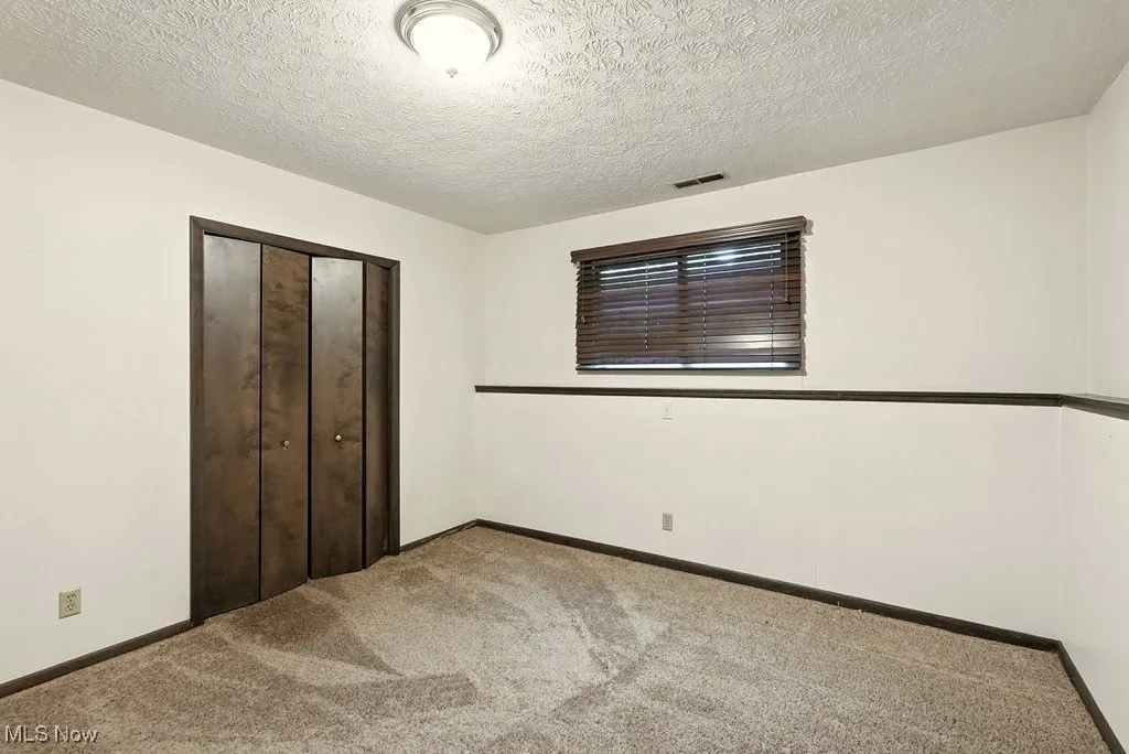 Unfurnished bedroom with carpet floors, a closet, and a textured ceiling