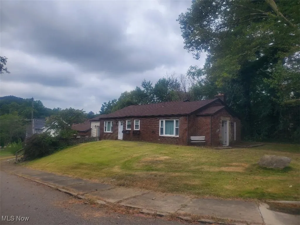 Ranch-style house with a front lawn, a chimney, and brick siding