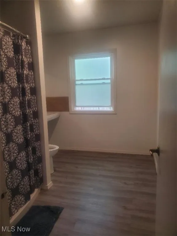 Full bath with dark wood finished floors and a stall shower