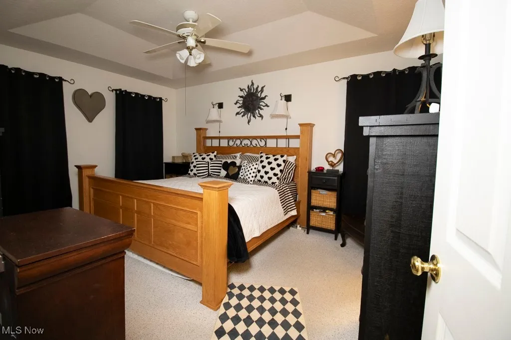 Bedroom with a raised ceiling and ceiling fan