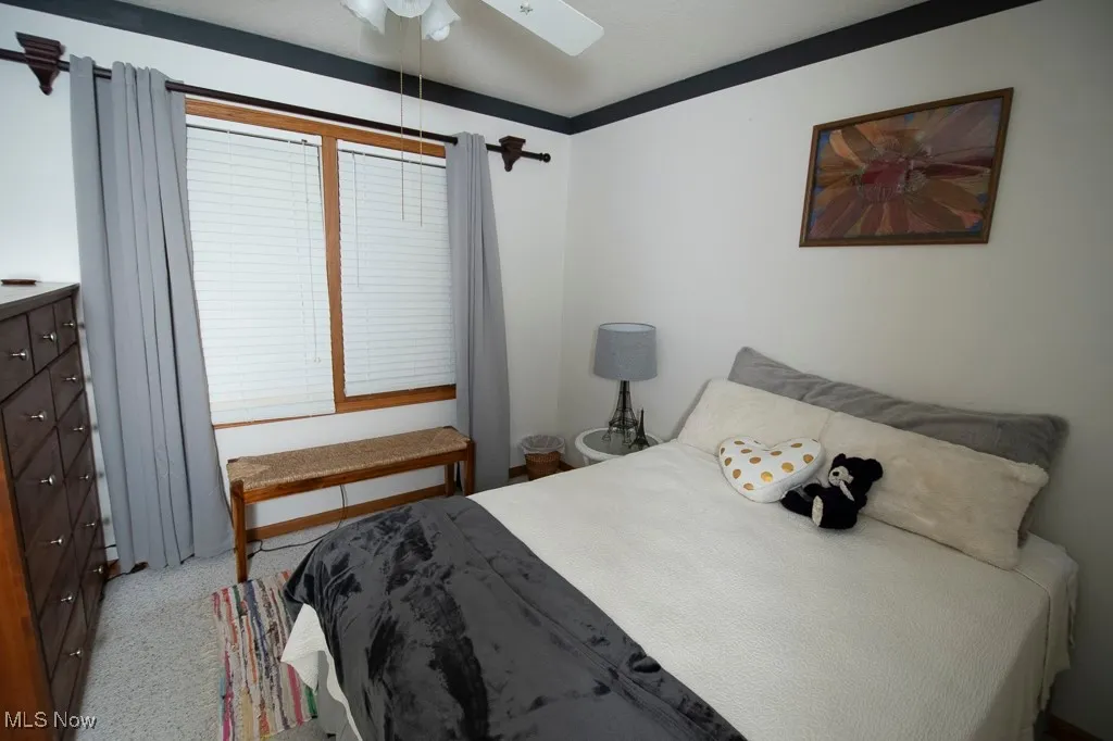 Bedroom with a ceiling fan and light carpet