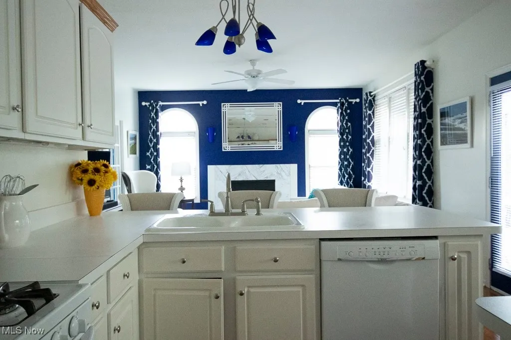 Kitchen featuring white appliances, light countertops, a peninsula, open floor plan, and ceiling fan