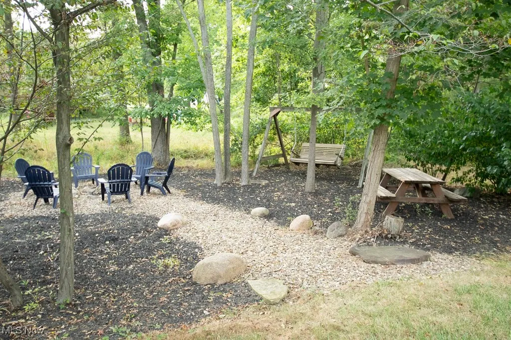 View of yard with an outdoor fire pit and view of scattered trees