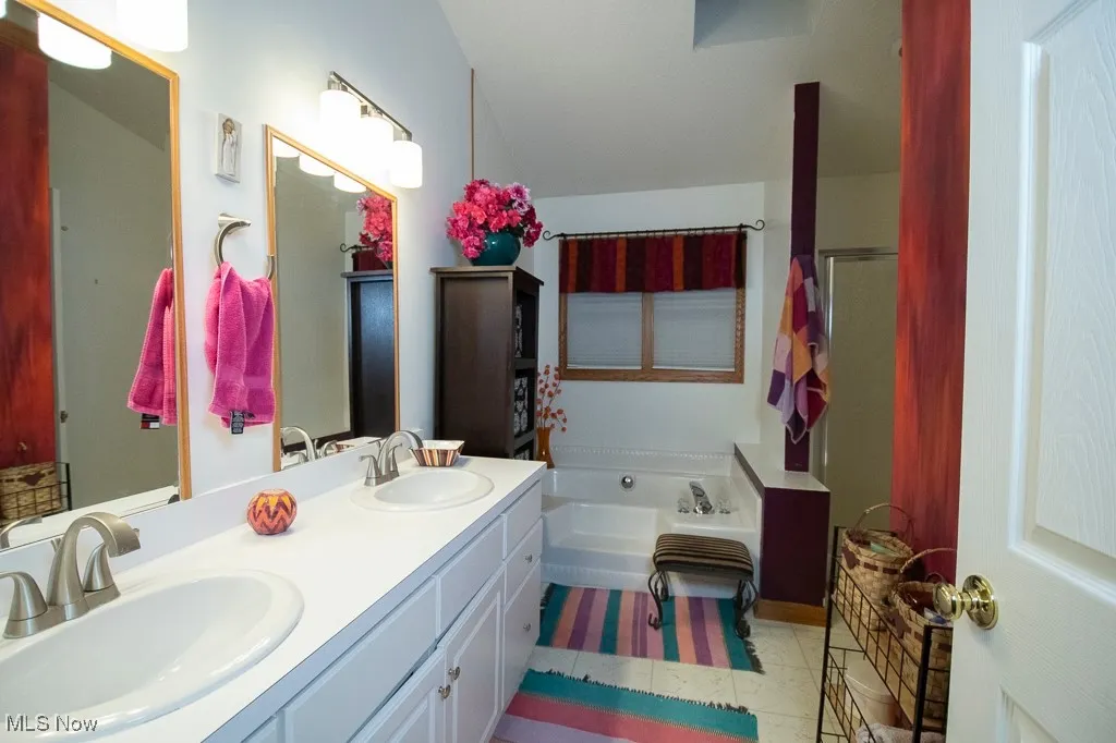 Bathroom featuring a stall shower, a garden tub, and double vanity