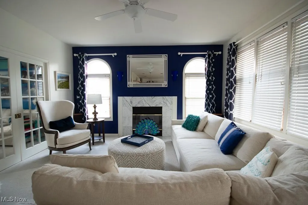 Carpeted living room featuring a fireplace and a ceiling fan