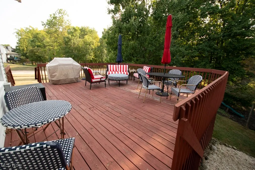 Deck with area for grilling, outdoor dining area, and view of wooded area