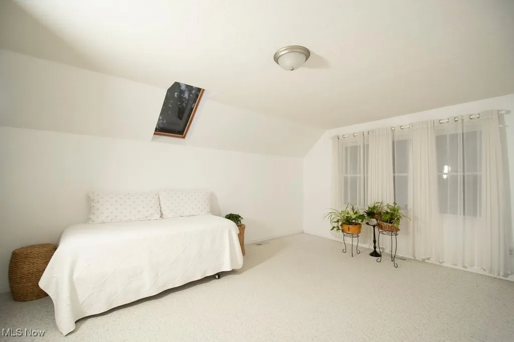 Carpeted bedroom featuring lofted ceiling and baseboards