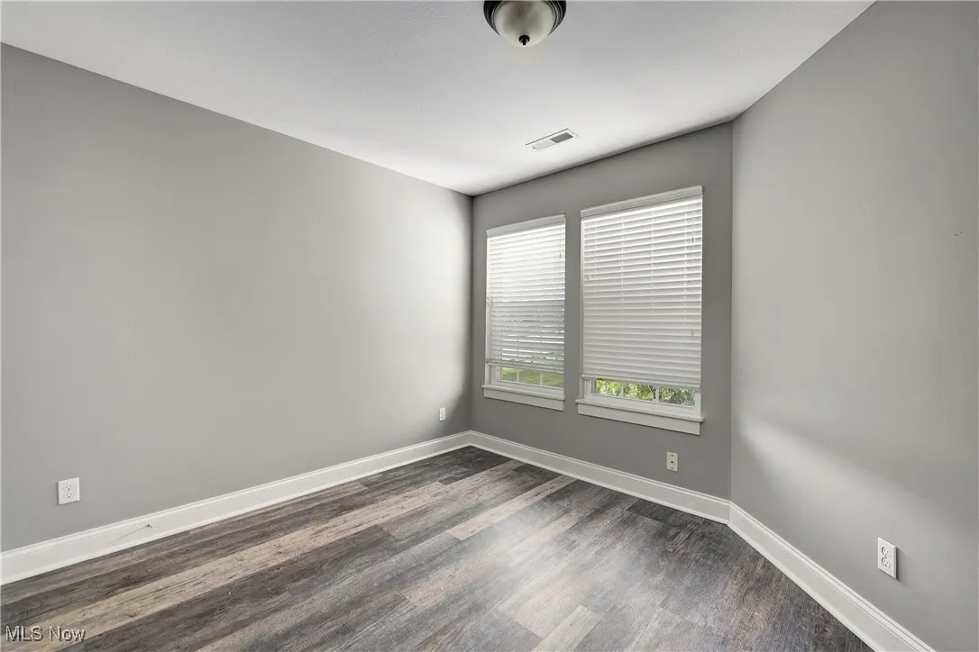 Unfurnished room featuring baseboards and dark wood-style flooring