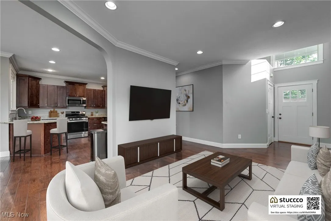 Living room featuring arched walkways, recessed lighting, dark wood finished floors, and ornamental molding