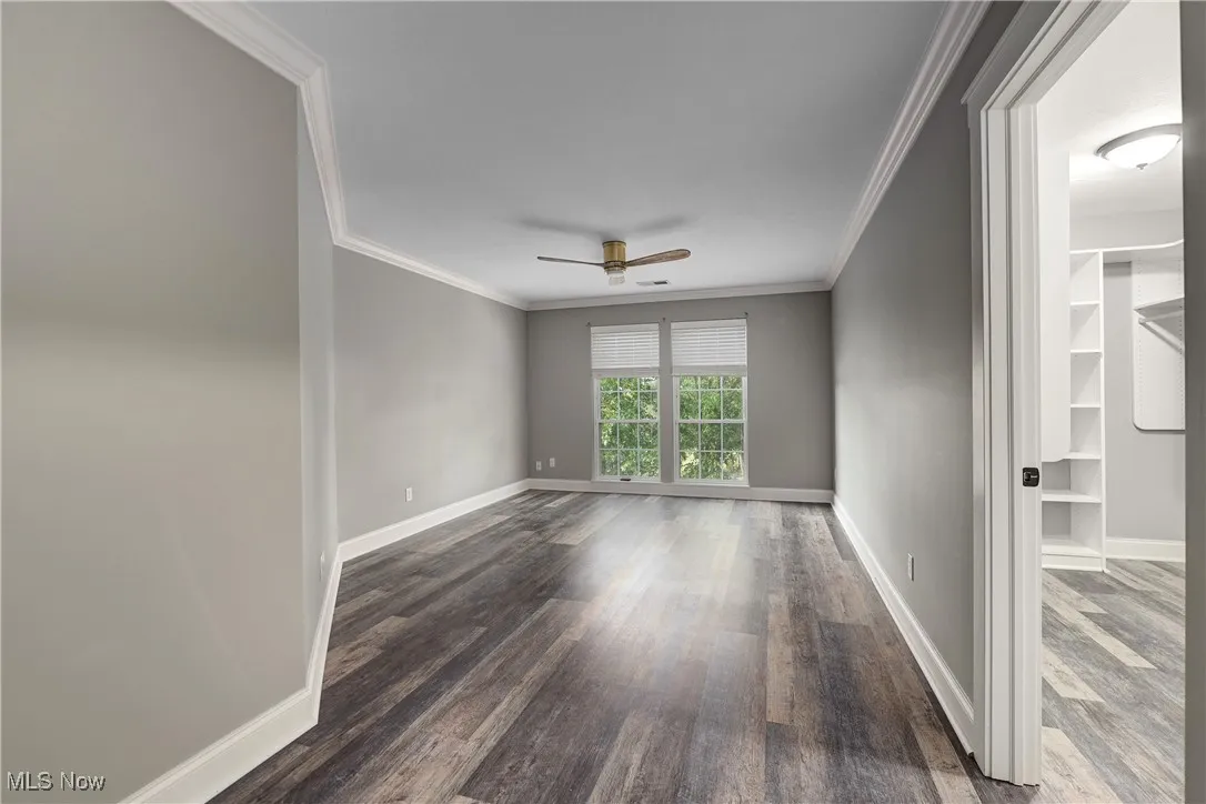 Empty room with ornamental molding, wood finished floors, and a ceiling fan