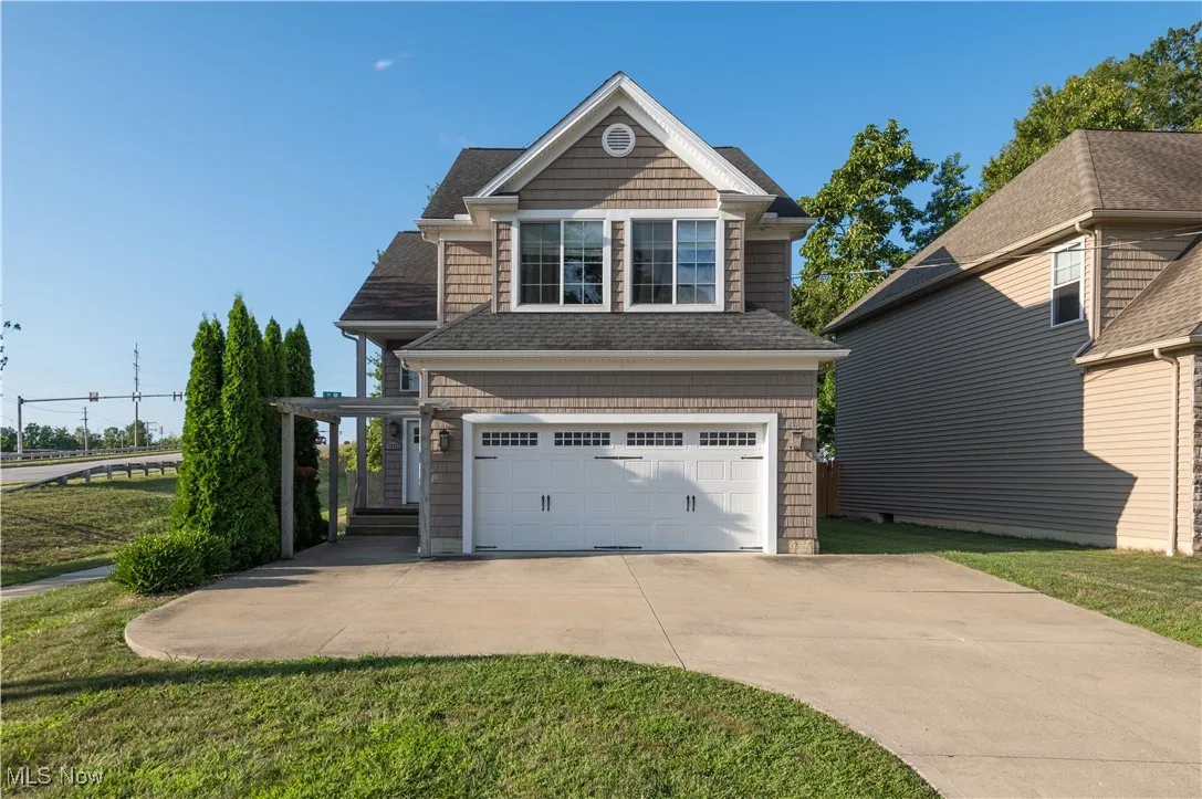 View of front of house featuring a garage, driveway, a front yard, and roof with shingles