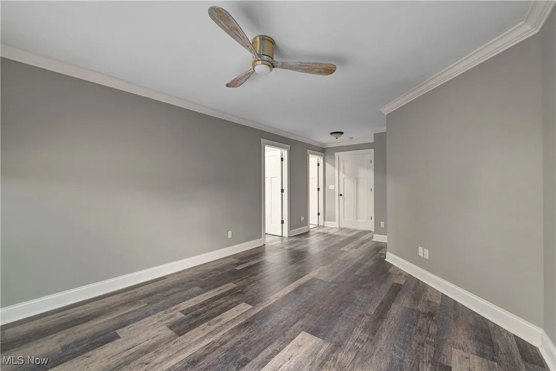 Unfurnished bedroom with ornamental molding, dark wood-style floors, and a ceiling fan