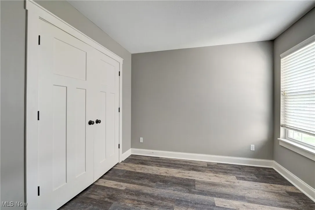 Unfurnished bedroom featuring dark wood finished floors and baseboards