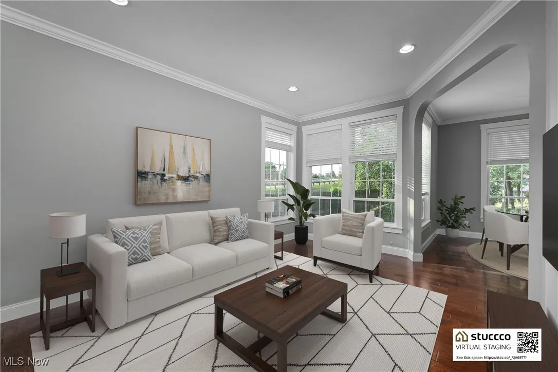 Living room with crown molding, dark wood-style floors, recessed lighting, and arched walkways