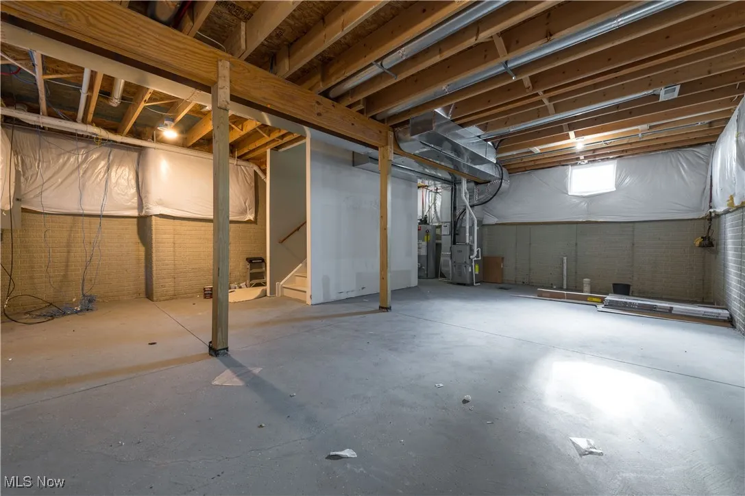 Basement with stairs, gas water heater, and heating unit