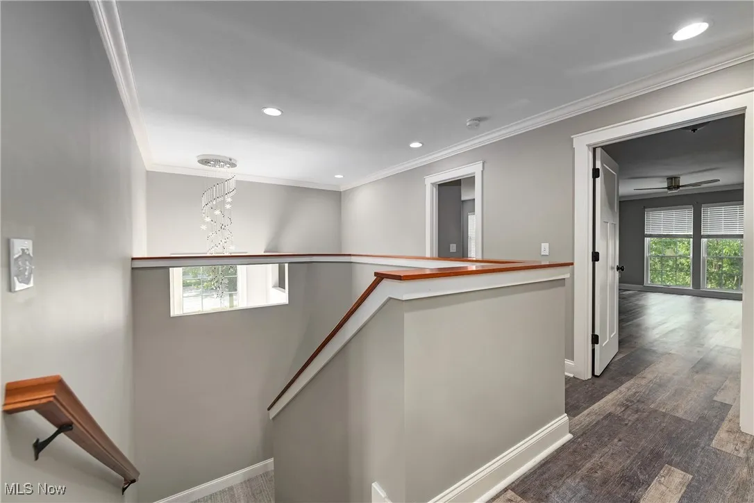 Hall with an upstairs landing, plenty of natural light, ornamental molding, recessed lighting, and dark wood-type flooring