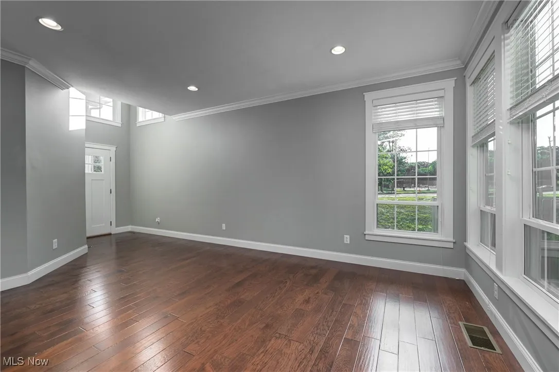 Empty room featuring ornamental molding, dark wood finished floors, plenty of natural light, and recessed lighting