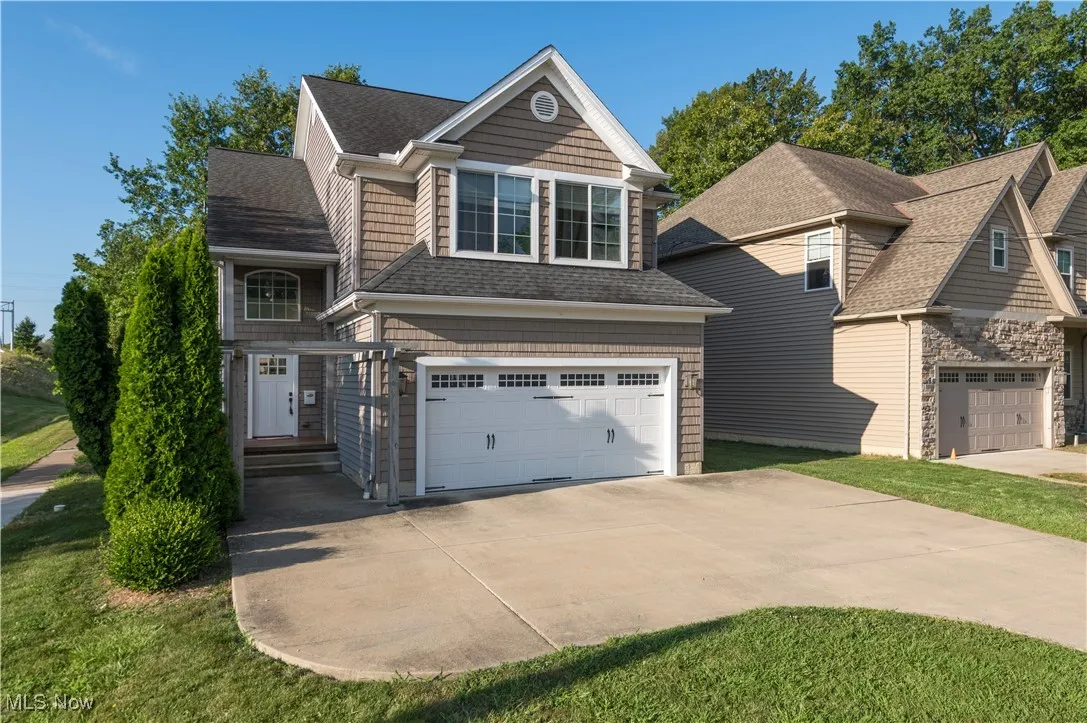 View of front facade featuring roof with shingles, a garage, and concrete driveway