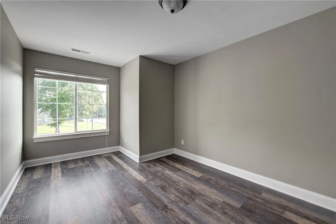 Spare room with dark wood-style floors and baseboards
