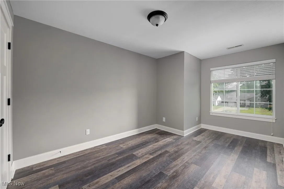Spare room with dark wood-style flooring and baseboards