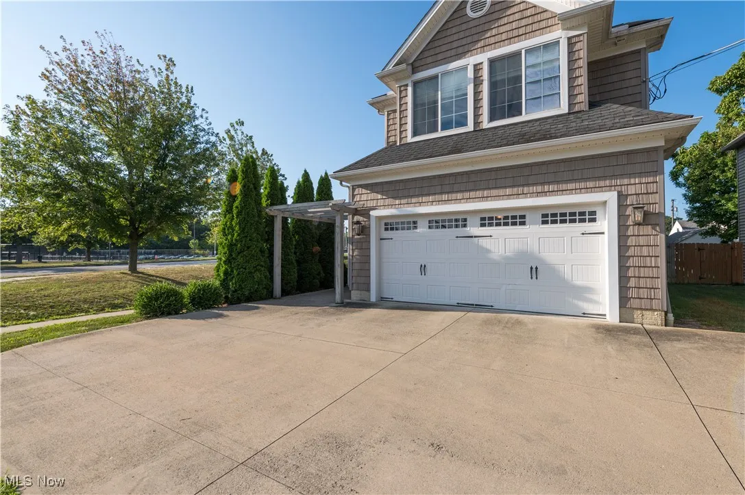 View of property exterior with an attached garage, driveway, and roof with shingles