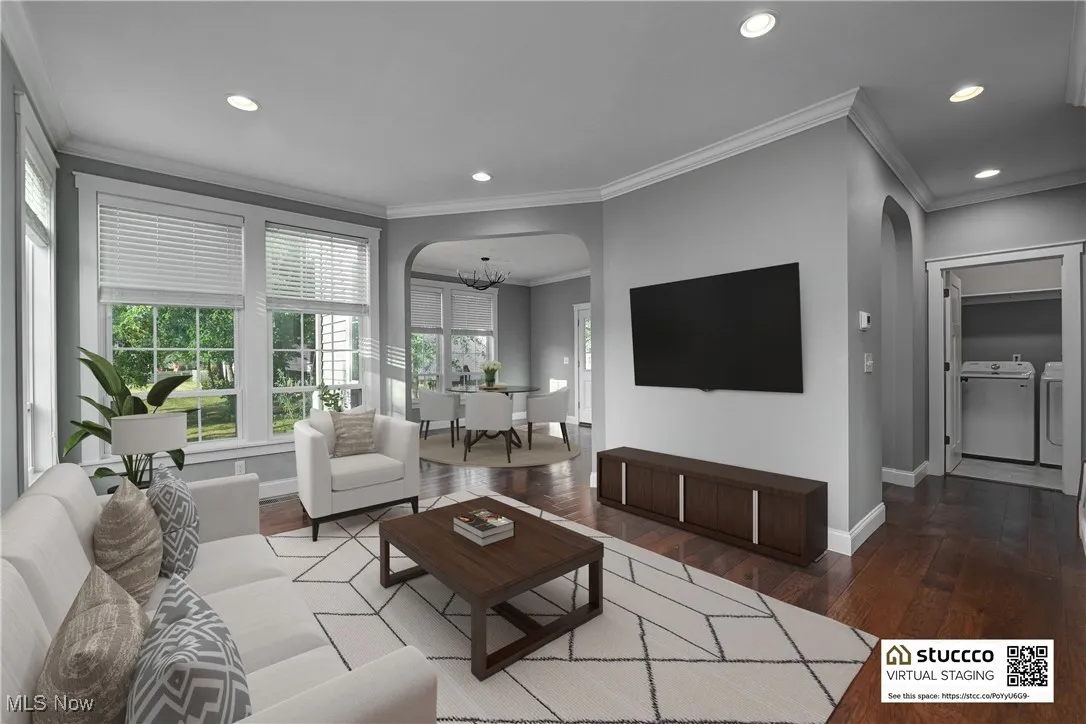 Living area featuring crown molding, dark wood-type flooring, a chandelier, arched walkways, and recessed lighting