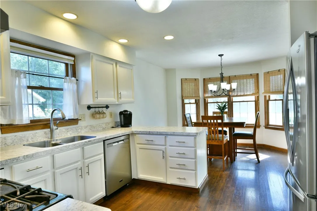 Kitchen with white cabinets, appliances with stainless steel finishes, recessed lighting, a peninsula, and a chandelier