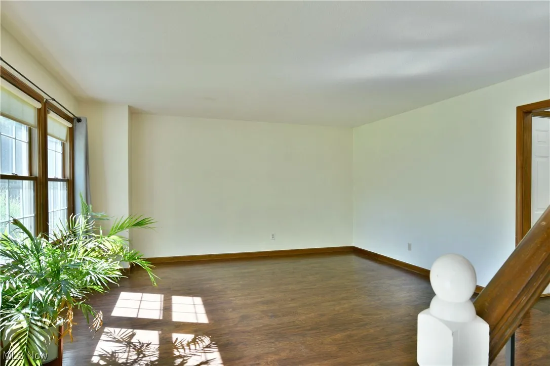 Empty room featuring dark wood-style flooring and baseboards