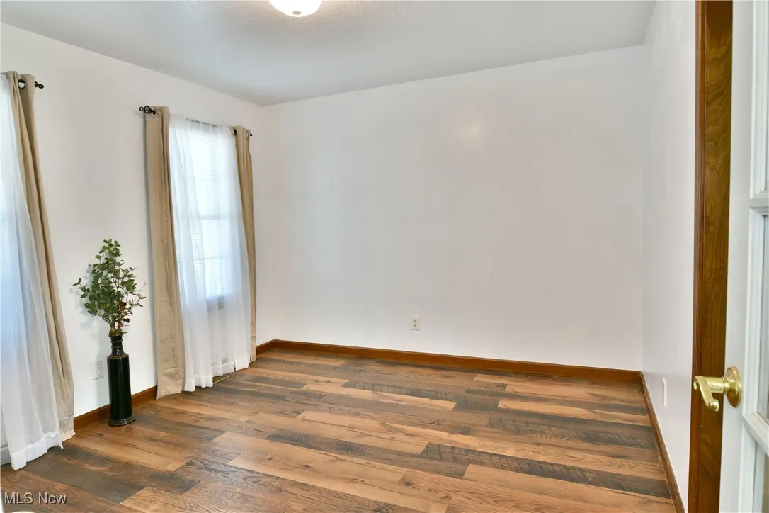 Empty room featuring dark wood-style floors and baseboards