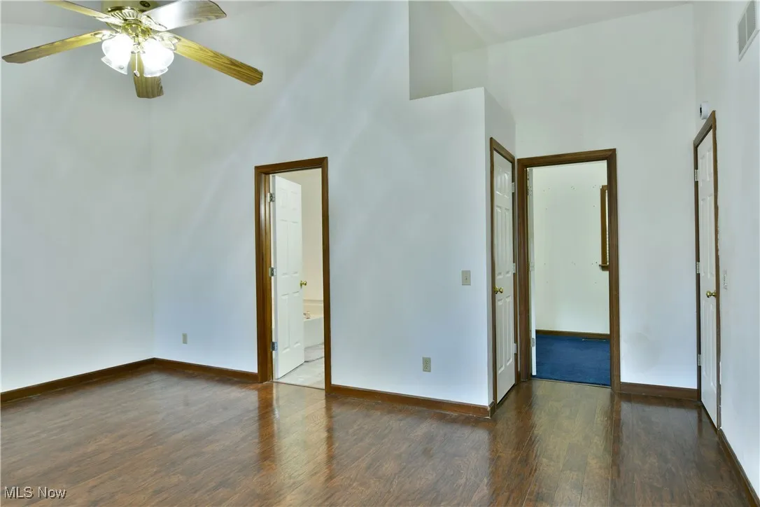 Unfurnished room with dark wood-type flooring, a high ceiling, and ceiling fan