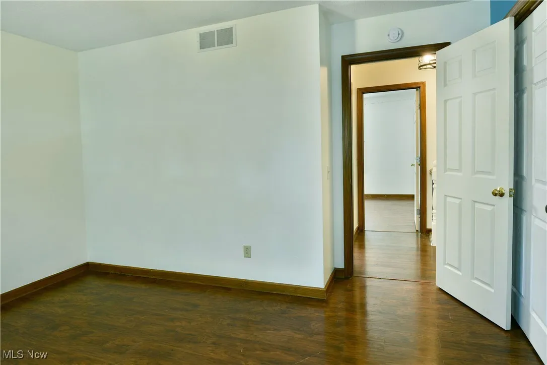 Unfurnished room featuring baseboards and dark wood-type flooring