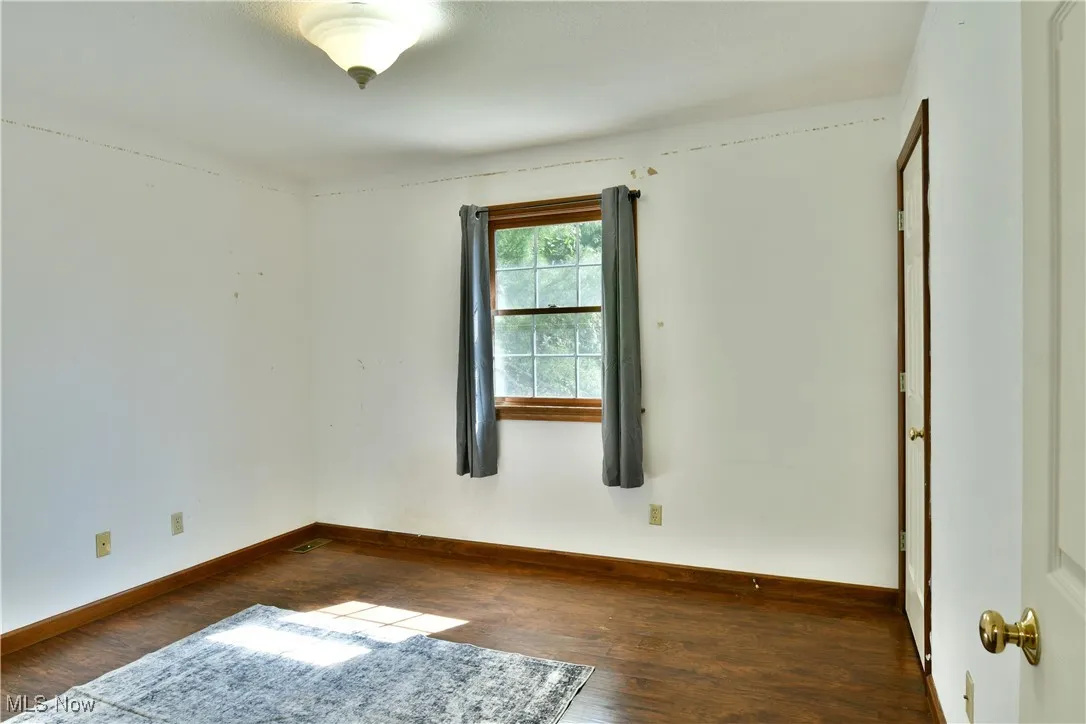 Spare room featuring dark wood-style floors and baseboards