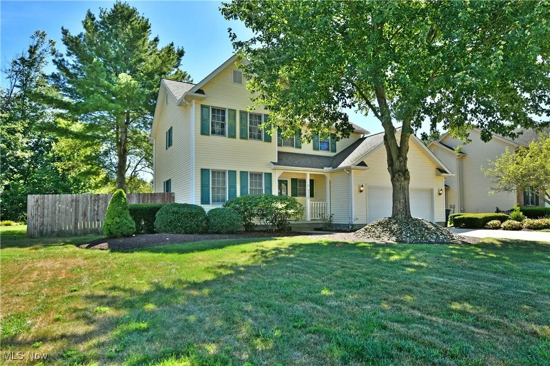 Traditional-style house featuring a garage, concrete driveway, and a porch