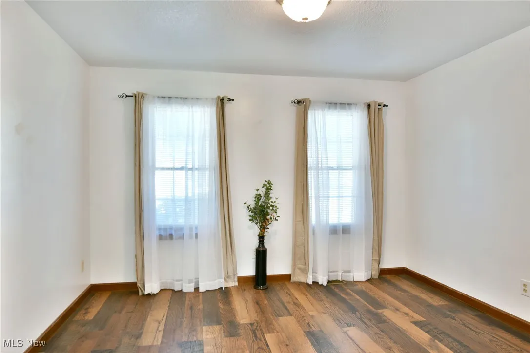 Unfurnished room with dark wood finished floors and baseboards